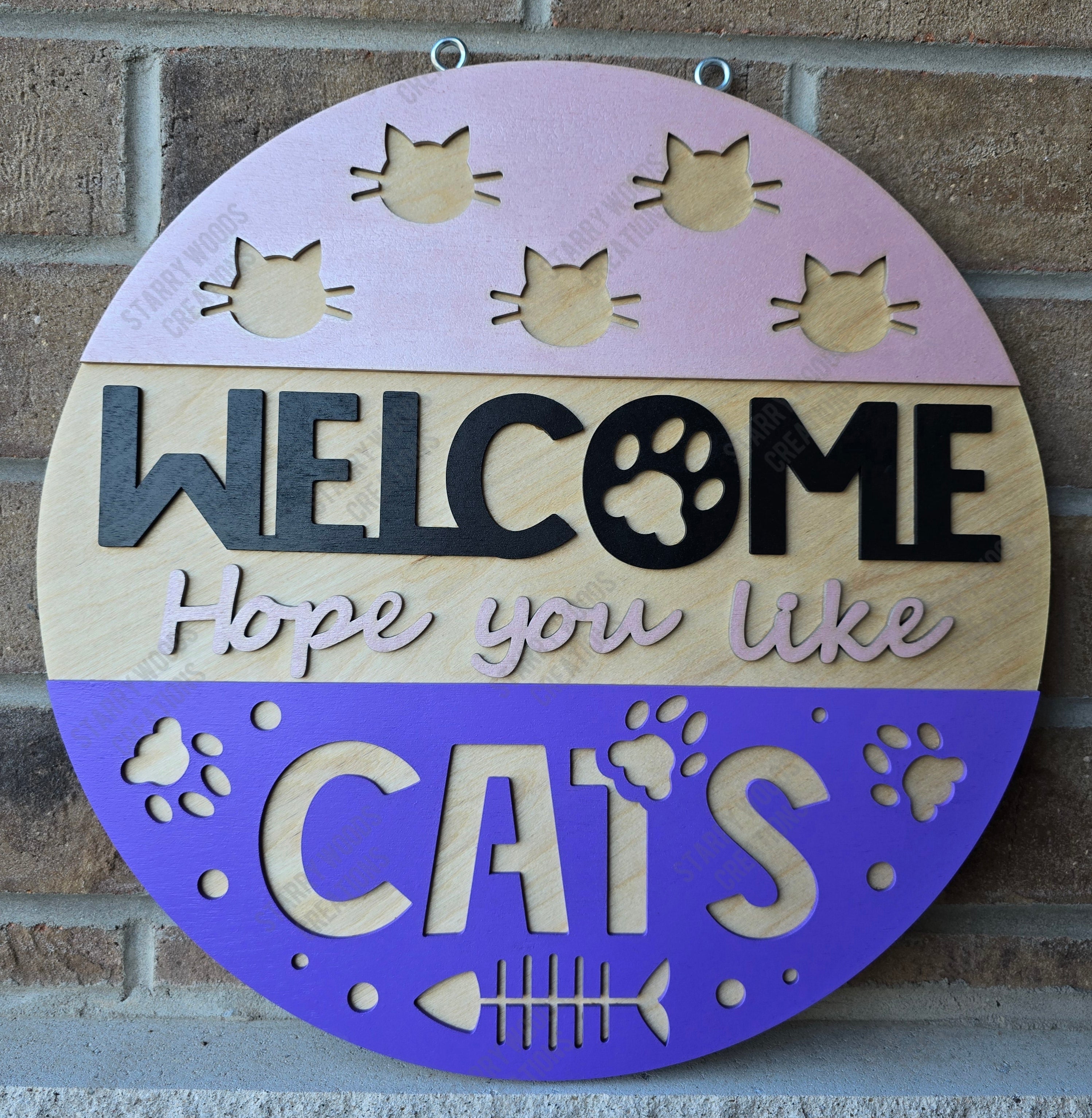 Round wooden sign with cat-themed text and designs on a brick wall background