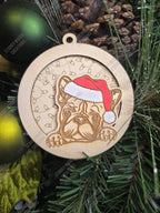 Wooden Christmas ornament with a french bulldog wearing a Santa hat, on a festive themed background on a tree.