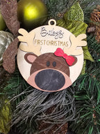Decorative round ornament with reindeer design and 'baby's First Christmas' text on a Christmas tree. Reindeer has one red bow on antler. Handmade in Ontario and Customizable.